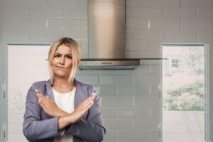 primo piano di una donna che dice no e cucina con cappa