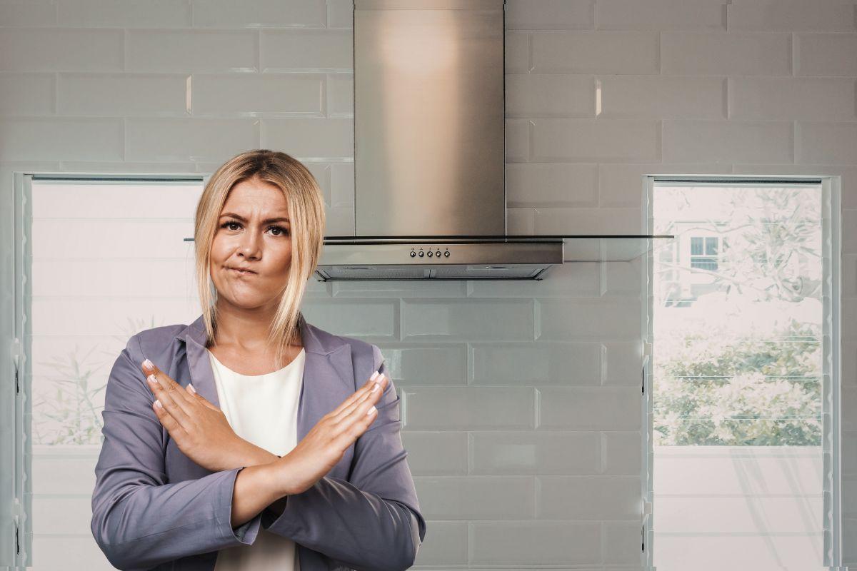 primo piano di una donna che dice no e cucina con cappa