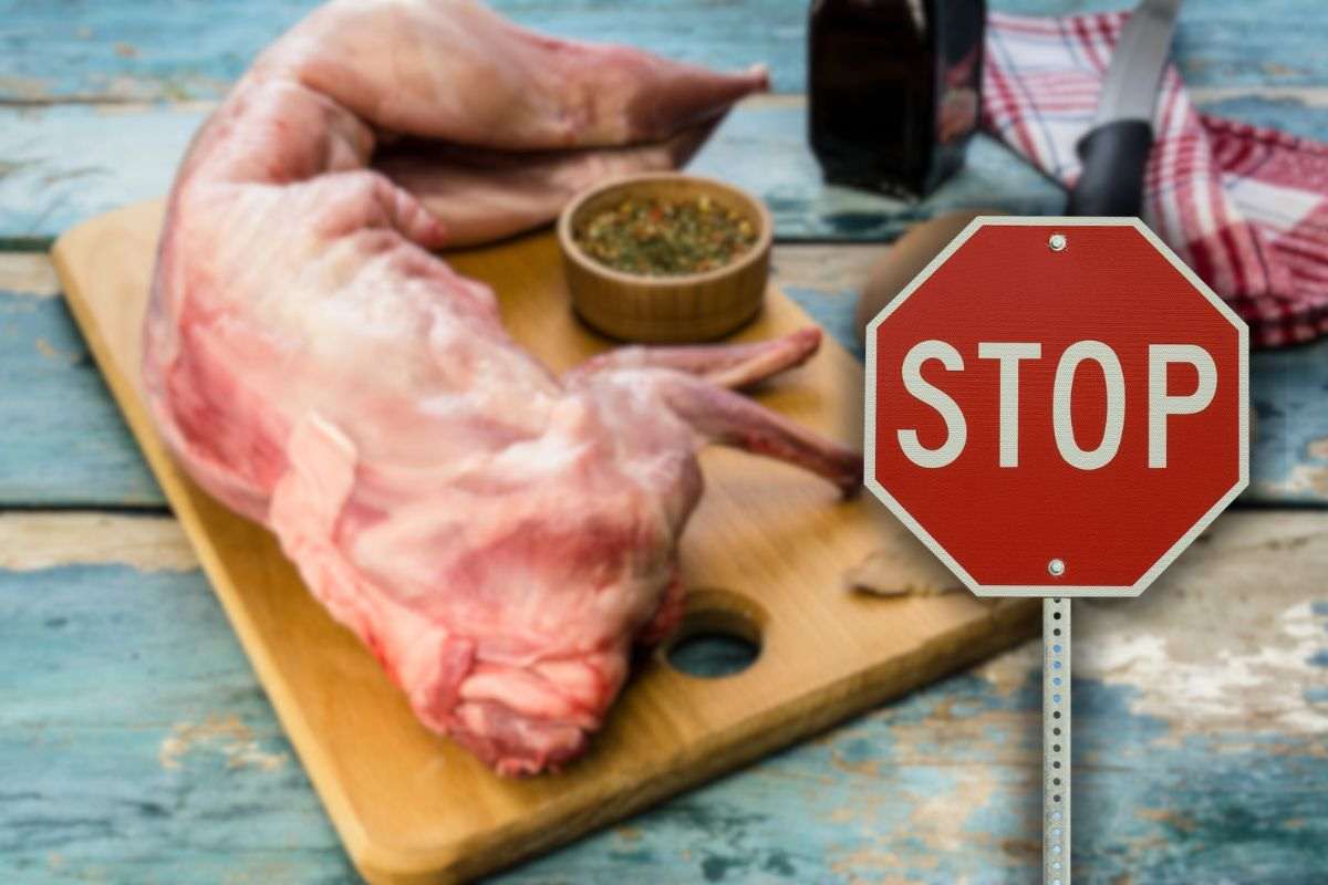 carne di coniglio su tagliere di legno con spezie e cartello stop