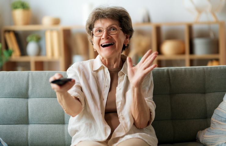 donna anziana felice che guarda tv