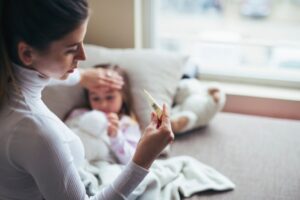 mamma con termometro in mano e con l'altra tocca fronte della figlia malata