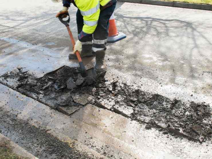 operaio che sistema una buca sulla strada