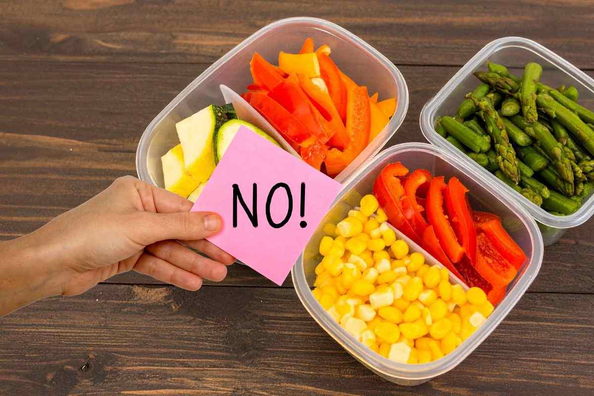 contenitori di plastica con delle verdure dentro e mano che mantiene un post-it con la scritta no
