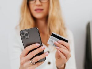 donna con cellulare e carta di credito in mano