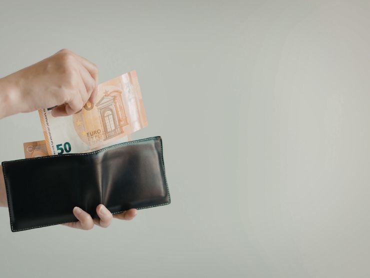 persona che mette soldi nel portafogli