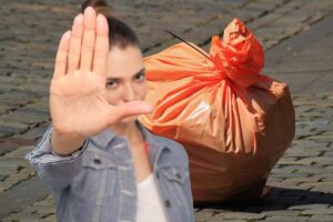 busta della spazzatura e donna che fa segno di stop con la mano