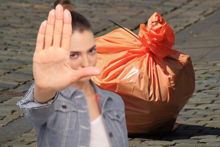 busta della spazzatura e donna che fa segno di stop con la mano