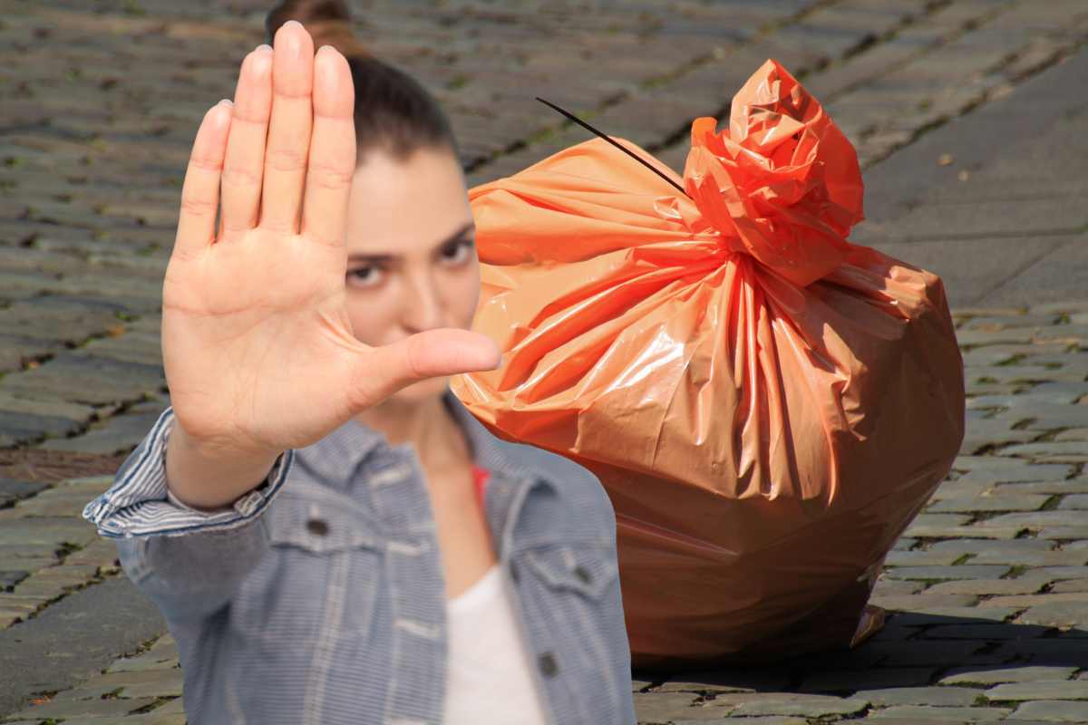 busta della spazzatura e donna che fa segno di stop con la mano